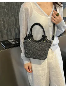 Detail view of stylish black tweed shoulder bag with leather handle and metal accents for women.