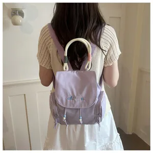 Mochila casual de lona en color morado claro con asa y bordado delicado para mujer