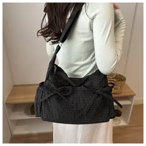 Dettaglio borsa a tracolla a quadretti neri, elegante fiocco, borsa casual giornaliera.