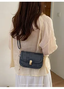 Détail de sac bandoulière texturé rétro, sac porté épaule chic avec fermoir métallique.