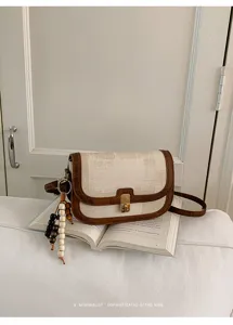 Détail sac bandoulière rétro bicolore, sacoche vintage avec pendentif perles en bois.