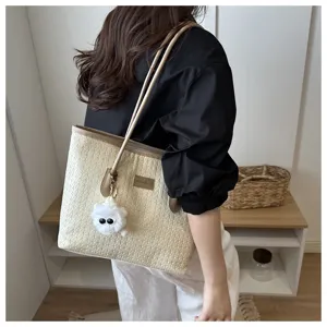 Schicke beige geflochtene Tasche mit braunen Henkeln und süßem flauschigen Anhänger für Damen.
