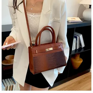 Detailed view of brown crocodile pattern handbag with gold metal lock closure and stylish top handles.