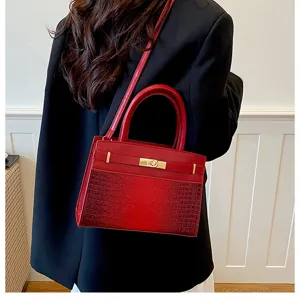 Red leather shoulder bag detail showing crocodile texture pattern and metallic lock closure.