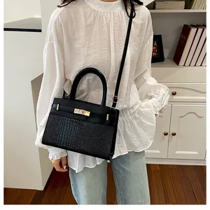 Detail view of stylish black handbag featuring crocodile texture and gold hardware.