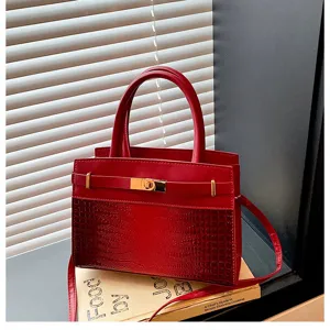 Red handbag with crocodile pattern, gold hardware, top handle and crossbody strap for women.