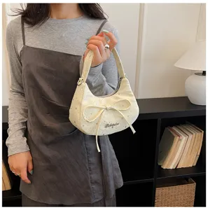 Detailed view of the chic cream shoulder bag featuring star patterns and a cute front bow.