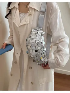 Close-up of a stylish silver sequin crossbody dumpling bag worn by a model in trench coat.