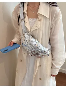 Detail view of a stylish silver sequin crossbody dumpling bag with wide strap worn by model.