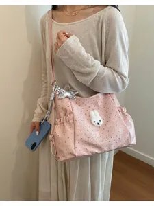 Dettaglio borsa a tracolla a pois rosa con toppa di coniglio carina e ciondolo stella argentata.
