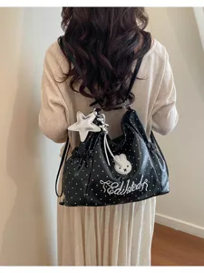 Dettaglio borsa shopper a pois neri, con ciondolo stella e ricamo coniglio, molto elegante.