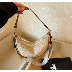 Vue détaillée du sac porté épaule en paille tressée croissant avec large sangle en tissu.