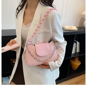 Dettaglio di borsa a tracolla rosa elegante con cinturino intrecciato e stelle.