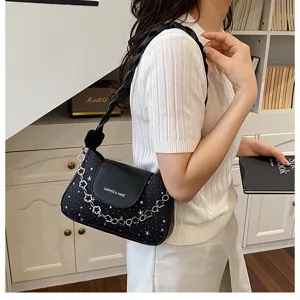 Primo piano dettagliato della elegante borsa a spalla nera con stampa stellata e catena.