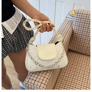 Primo piano della borsa a tracolla bianca con motivo a stelle e catena elegante.