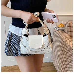 Dettaglio della borsa a tracolla bianca in pelle con motivo a stelle e catena metallica.