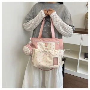 Pink polka dot canvas shoulder bag featuring a small coin purse and front pocket detail.