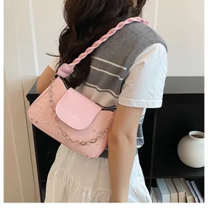 Dettaglio borsa a spalla rosa con catena floreale e pelle testurizzata stile elegante.