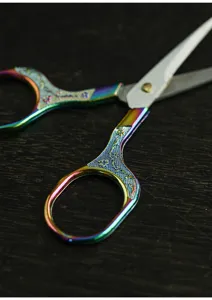 Close-up detail of vintage tea scissors with rainbow titanium finish and exquisite carved handle.