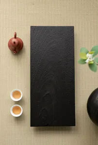 Detailed view of the dark charcoal-burned wooden tea tray surface texture, wabi-sabi tea setup.