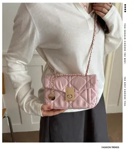 Detail shot of pink quilted chain shoulder bag with metal lock, chic designer style.