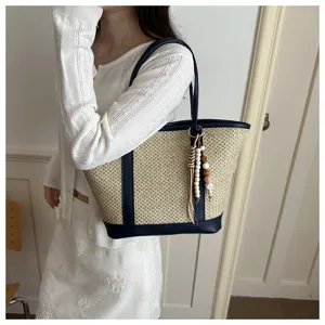 Stijlvolle casual strooien tote tas met blauwe rand en kralenhanger voor de zomer.
