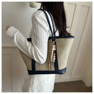 Zomerse geweven strooien tote tas detail met schouderband en decoratieve kraal hanger.