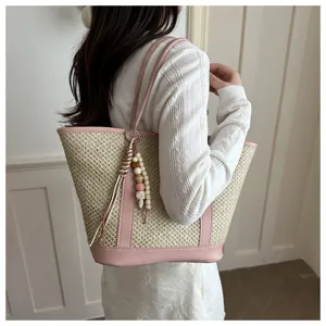 Zomerse geweven strooien tote bag met roze PU-afwerking en houten kralenhanger.