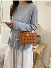 Borsa a tracolla marrone matelassé con elegante chiusura a V in metallo e design chic.