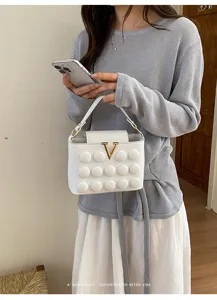 Borsa a tracolla bianca con bolle eleganti e fibbia V dorata, dettaglio borsa donna alla moda.
