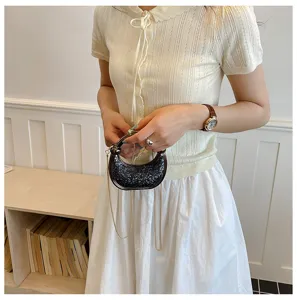Mini acrylic glitter evening bag detail, sparkling texture and chic chain strap design.