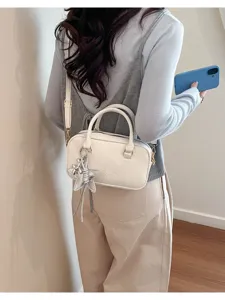 Detail shot of white bowling bag worn by model, featuring star charm and shoulder strap.