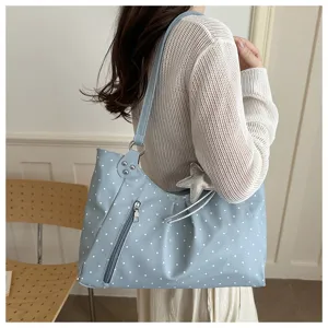 Close-up view of the light blue polka dot shoulder bag, showing zipper and star charm.