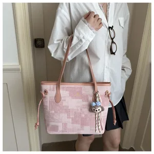 Stilvoller rosa geometrischer Eimerbeutel mit braunen Griffen und niedlichem Plüschanhänger.