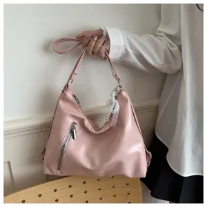 Détail de sac bandoulière hobo en cuir PU rose, avec poche zippée avant et charm perle mignon.