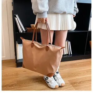 Large capacity nylon travel bag with brown leather handles and zipper closure for women daily use.