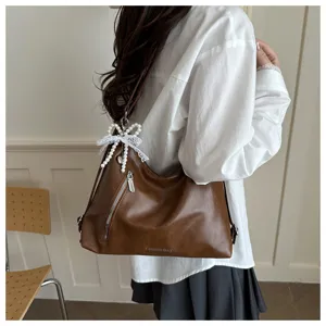 Sac bandoulière en cuir marron avec pendentif nœud perlé, élégant sac pour le quotidien.