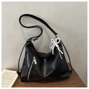Élégant sac à main bandoulière noir en cuir synthétique avec chic pendentif nœud perles.