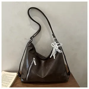 Vue détaillée du sac épaule en cuir PU marron foncé avec pendentif nœud perles et fermeture.
