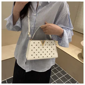 Vue détaillée du sac bandoulière blanc à clous avec fermoir logo V doré et poignée.