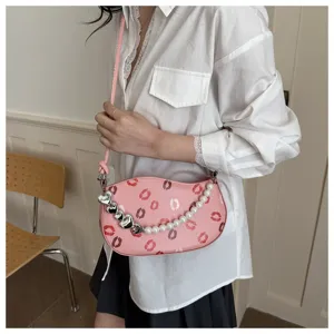 Sac bandoulière rose motif lèvres avec chaîne de perles et charms cœur élégants.