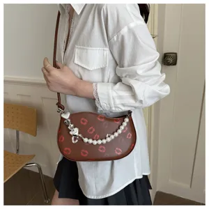 Sac bandoulière marron tendance avec imprimé lèvres, chaîne en perles et design chic.
