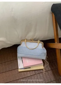 Détail du sac à main rétro à fermoir baiser rayé bleu et blanc avec chaîne élégante.