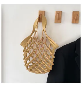 Detailed shot of the yellow leather mesh handbag hanging on wall, showing hollow design.