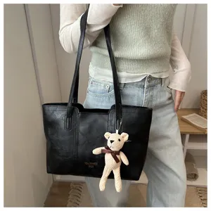 Vista dettagliata della borsa tote in pelle nera con grazioso ciondolo orsetto in maglia.