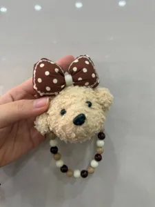 Gros plan détaillé du joli charm de sac en peluche chiot avec son nœud à pois marron.