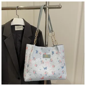 Detailansicht der hellblauen strukturierten Tote-Bag mit Schmetterlings- und Blumen-Print.