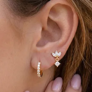 Gedetailleerde close-up van stijlvolle gouden creolen en sprankelende zirconia oorbellen.