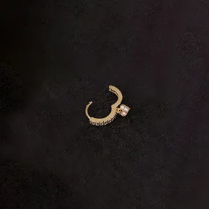 Goldener Piercing-Ohrring mit funkelnden Zirkoniasteinen und filigranem Blumen-Anhänger.