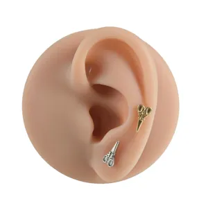 Titan Schere Piercing Ohrring Detailansicht mit goldenen und silbernen Ohrsteckern Ohr.